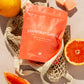 Grapefruit Garden product package on a textured surface with grapefruit slices and an orange.